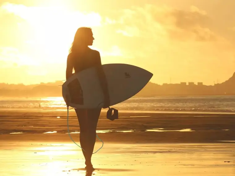 Surfista com prancha ao pôr do sol à beira-mar